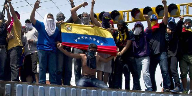 TOPSHOTSProtesters stand atop a container at a roadblock at a street of San Cristobal, capital of the western border state of Tachira, Venezuela, on February 21, 2014. At least 25 people were injured in late Saturday clashes with security forces that were some of the most serious to date. Venezuela's president on Sunday called for crisis talks in an attempt to defuse weeks of often deadly anti-government protests that have brought the biggest challenge yet to his regime. AFP PHOTO / LUIS ROBAYO