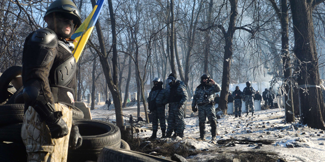 An anti-government opposition activist guards as Berkut special police examine a barricade of the opposition in  Kiev on February 2, 2014. Tens of thousands of protesters rallied in Ukraine on Sunday in a bid to wring new concessions from President Viktor Yanukovych, buoyed by pledges of support from Europe and the United States. More than 50,000 people could be seen on Kiev's barricaded Independence Square - that has become the epicentre of a two-month protest movement -- and thousands more were arriving. AFP PHOTO/ SERGEI SUPINSKY