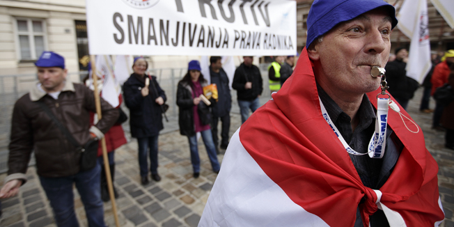 Zagreb, 260214.Markov Trg.Prosvjednici protiv donosenja zakona o radu u predlozenom obliku kojim se, kako tvrde sindikati, smanjuju radnicka prava u korist poslodavaca i kapitala, okupili su se na Trgu bana Jelacica odakle su nesto prije 9 sati krenuli prema Markovom trgu gdje æe odrzati prosvjed ispred Hrvatskog sabora.U Saboru se ocekuje rasprava o predlozenim izmjenama Zakona o radu, koju ce prosvjednici pratiti preko velikog video zida, a sindikalni celnici sa saborske galerije.Na fotografiji: prosvjednici s transparentom i zvizdaljkom.Foto: Dragan Matic / CROPIX