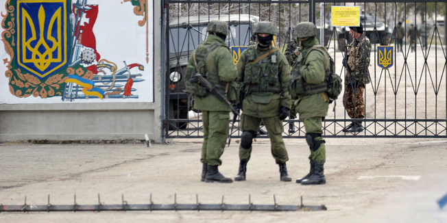 Ukrainian soldiers (R) stand guard inside their base blocked by Russian troops in Perevalnoye, near Simferopol, on March 6, 2014. Pro-Moscow authorities in Crimea on March 6 asked Russian President Vladimir Putin to examine a request for their region to join the Russian Federation, which will be put to a referendum on March 16. AFP PHOTO/ GENYA SAVILOV