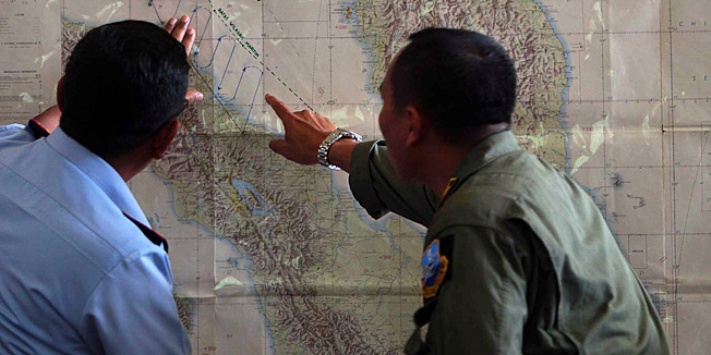 Indonesian Air Force officials at Medan city military base plot the Indonesian military search operation for the missing Malaysian Airlines flight MH370 on March 12, 2014 in the area of Malacca Strait, a sea passageway between Indonesia (seen left of the map) and Malaysia (seen right on the map). Malaysia faced a storm of criticism on March 12 over contradictions and information gaps in the hunt for a missing airliner with 239 people on board, as the search zone dramatically veered far from the intended flight path.       AFP PHOTO / ATAR
