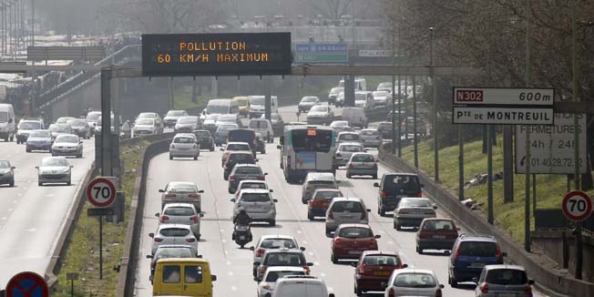 Vehicles drive past an information board asking to limit their speed to 60km/h on the ring road on March 15, 2014 in Paris. Overall, more than 30 departments in France were hit by maximum level pollution alerts, prompting Ecology Minister Philippe Martin to say air quality was 