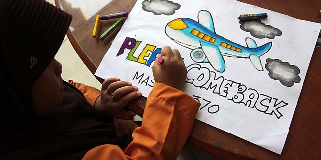 An Indonesian student writes a message expressing prayers and well-wishes for passengers onboard missing Malaysia Airlines (MAS) flight MH370 in Medan, North Sumatra, on March 15, 2014.  Investigators now believe the Malaysian jet that vanished was commandeered by a 