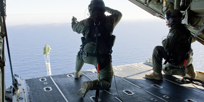 A photo taken on March 20, 2014, shows Royal Australian Air Force Loadmasters, Sergeant Adam Roberts (L) and Flight Sergeant John Mancey (R), preparing to launch a Self Locating Data Marker Buoy from a C-130J Hercules aircraft in the southern Indian Ocean as part of the Australian Defence Force's assistance to the search for Malaysia Airlines flight MH370.  Australia resumed the search 21 March for possible wreckage from a missing Malaysian jetliner in a remote, storm-swept stretch of the Indian Ocean, hoping for better weather as spotters seek to identify the objects shown on grainy satellite images.  ----EDITORS NOTE ----RESTRICTED TO EDITORIAL USE MANDATORY CREDIT 