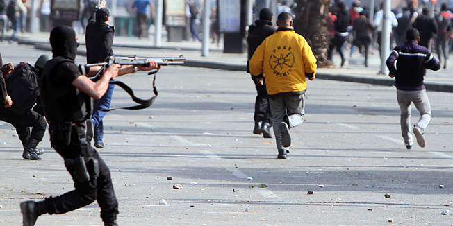 Riot police are seen outside the grounds of Cairo University as Egyptian students, supporters of ousted Islamist president Mohamed Morsi, demonstrate inside the grounds and on the streets leading to their campus in the capital Cairo, on March 19, 2014.  Morsi was ousted by the military last July, and his supporters have staged near-daily rallies since then.  AFP PHOTO / MOHAMED EL-SHAHED