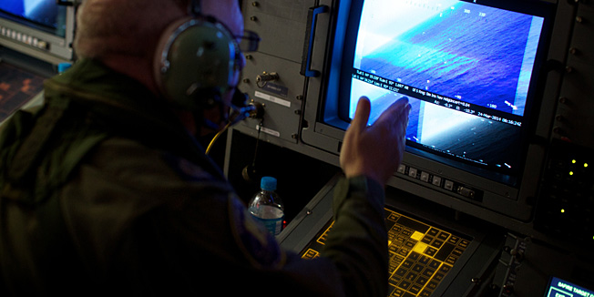 A crewman on board an RAAF AP-3C Orion aircraft looka at his radar screens whilst searching for the missing Malaysia Airways Flight MH370 over the Indian Ocean on March 24, 2014. Australian Prime Minister Tony Abbott told Parliament on March 24 that a Royal Australian Air Force P-3 Orion aircraft had located two new objects floating in the southern Indian Ocean.  AFP PHOTO/POOL/RICHARD WAINWRIGHT