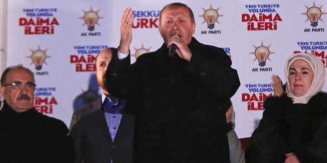 Turkey's Prime Minister Recep Tayyip Erdogan (C) addresses to the crowd from the balcony of Justice and Development Party headquarters in Ankara, Turkey on March 31, 2014. The party of Turkish Premier Recep Tayyip Erdogan took a strong early lead in local elections, despite turbulent months marked by mass protests, corruption scandals and Internet blocks. A photo of Turkish Premier Recep Tayyip Erdogan is seen on the flag at right.     AFP PHOTO / ADEM ALTAN