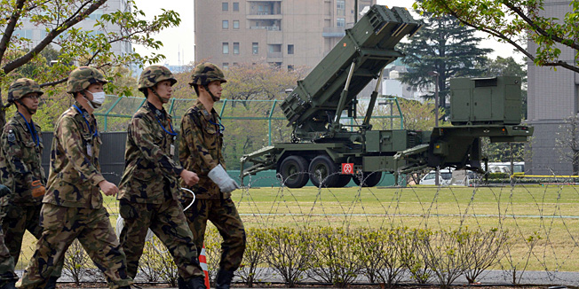 Officers of Japan's Ground Self-Defense Force (SDF) walk in front of Patriot Advanced Capability-3 (PAC-3) surface-to-air missile launchers at the Defence Ministry in Tokyo on April 9, 2013. Japan has deployed Patriot missiles in its capital as it readies to defend the 30 million people who live in greater Tokyo from any North Korean attack.    AFP PHOTO / Yoshikazu TSUNO