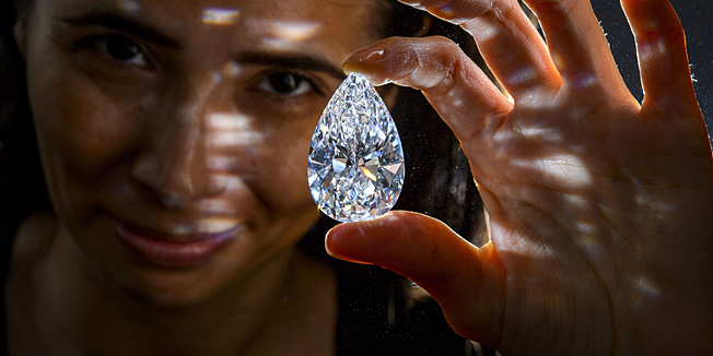 (FILES) A file picture taken on April 30, 2013 shows a model posing with a pear-shaped perfect D color, Type IIA Flawless clarity diamond weighing 101.73 carats during a press preview by Christie's auction house in Geneva. The perfect colourless diamond was auctioned for record $23.5 million during sales on May 15, 2013 in Geneva.  AFP PHOTO / FABRICE COFFRINI