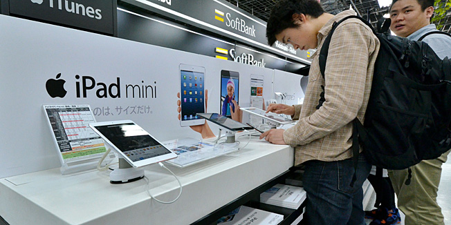 Customers check the Apple's tablet iPads at a Tokyo electric shop on May 31, 2013 as Apple was reportedly boosting the price of iPads sold in Japan by as much as 20 percent for weaken yen.  Household spending was also weaker than expected while consumer prices fell 0.4 percent year-on-year in April, underscoring the tough task in reversing years of deflation that has crimped private spending and business investment.   AFP PHOTO / Yoshikazu TSUNO