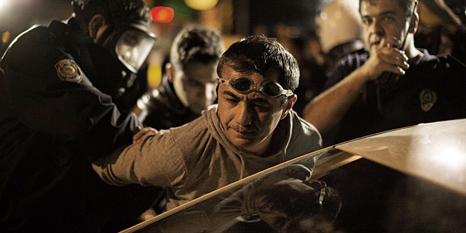 Turkish anti-riot police arrest a goggle-wearing protester during clashes with demonstrators in Ankara June 13, 2013. The man drove past a group of police flashing the victory sign and was then stopped, removed from his car and detained. Turkish Prime Minister Recep Tayyip Erdogan on June 12, 2013 said he would consider holding a referendum on plans to redevelop an Istanbul park that have sparked nationwide protests, in his first major concession in nearly two weeks of anti-government unrest.  AFP PHOTO/MARCO LONGARI