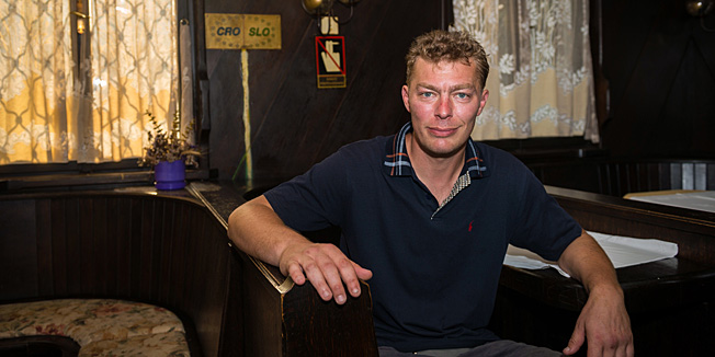 TO GO WITH AFP STORY BY SIM SIM WISSGOTTSasa Josip Kalin, owner of Restaurant Kalin, poses for photo in his restaurant with border sign behind him in Obrezje, Slovenia on June 18, 2013.  Obrezje stands on the eastern edge of Slovenia and 