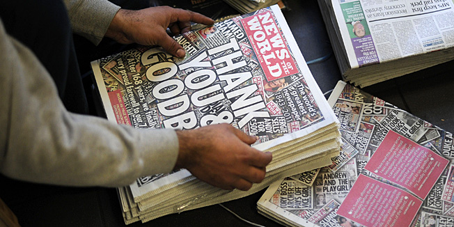(FILES) In this file picture taken on July 10, 2011 a man prepares copies of the last edition of the British tabloid newspaper News of the World for sale at a shop in south London on July 10, 2011.  British police arrested six former News of the World journalists on February 13, 2013 in a new probe into alleged phone hacking at Rupert Murdoch's now-closed tabloid, Scotland Yard said.  AFP PHOTO / CARL COURT