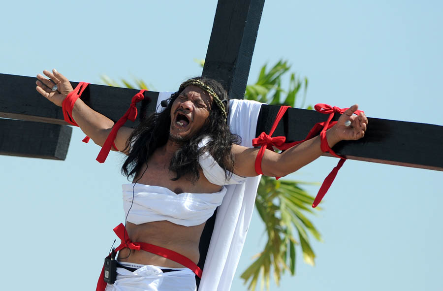 Philippine Christian devotee Ruben Enaje grimaces in pain after being nailed to the Cross by men dressed as Roman soldiers during a re-enactment of the crucifixion of Jesus Christ on Good Friday in San Fernando City, Pampanga province, north of Manila on March 29, 2013.  Roman Catholic fanatics in the Philippines had themselves nailed to the cross March 29, in a bloody display of religious frenzy as the Christian world marked the day Jesus was crucified. AFP PHOTO/NOEL CELIS