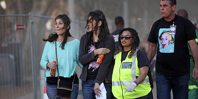 A injured woman, second left, holds her arm as she walks with medical personnel, second right, after she and others were injured during a concert by Linkin Park in Cape Town, South Africa, Saturday, Nov. 7, 2012. The city of Cape Town, South Africa, says that 20 people have been injured after scaffolding collapsed because of high winds outside a concert for Linkin Park. (AP Photo)