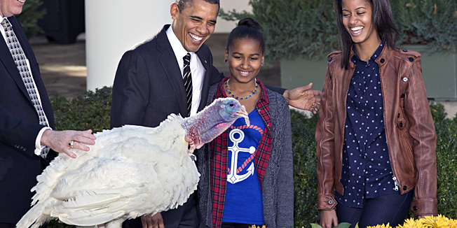 President Barack Obama, with daughters Sasha, center, and Malia, right, carries on the Thanksgiving tradition of saving a turkey from the dinner table with a 