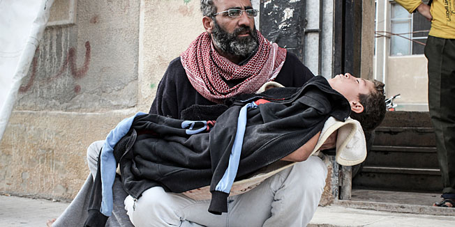 In this Sunday, Nov. 18, 2012 photo, a father comforts his son who has just undergone surgery for a bullet wound in his left shoulder outside a field hospital  in the northwestern city of Maraat al-Numan, Syria. After months of fierce fighting for control of the vital Aleppo-Damascus highway, rebels have succeeded in pushing the Syrian army out of the center of Maraat al-Numan located on the highway between Aleppo and Hama. (AP Photo/Mustafa Karali)
