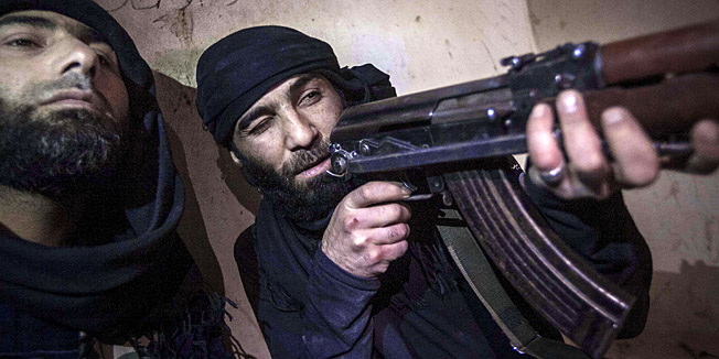 In this Wednesday, Dec. 5, 2012 photo, a Free Syrian Army fighter aims his weapon during heavy clashes with government forces in Aleppo, Syria. (AP Photo/Narciso Contreras)