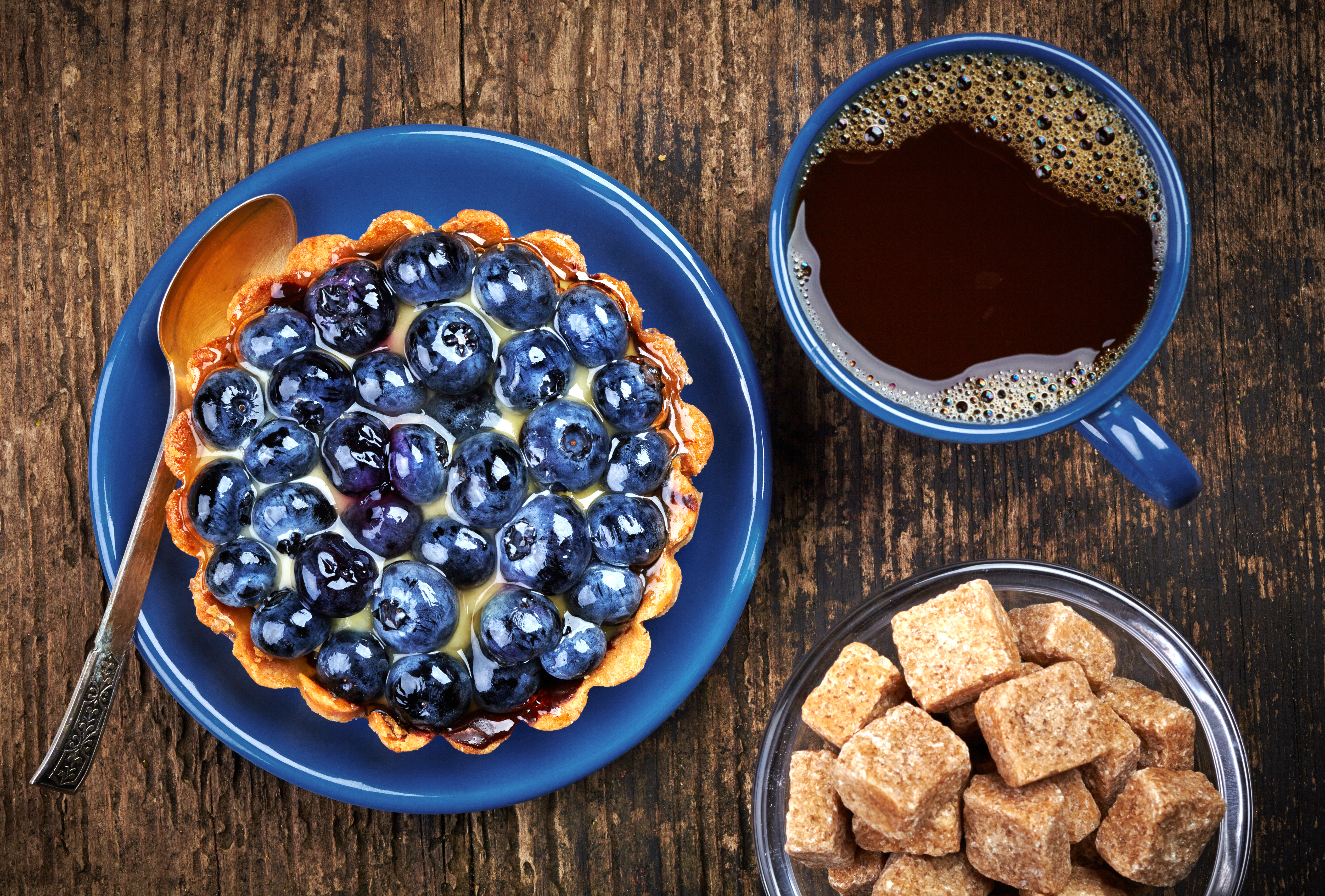 Plate of blueberry tart and cup of coffee on wooden background