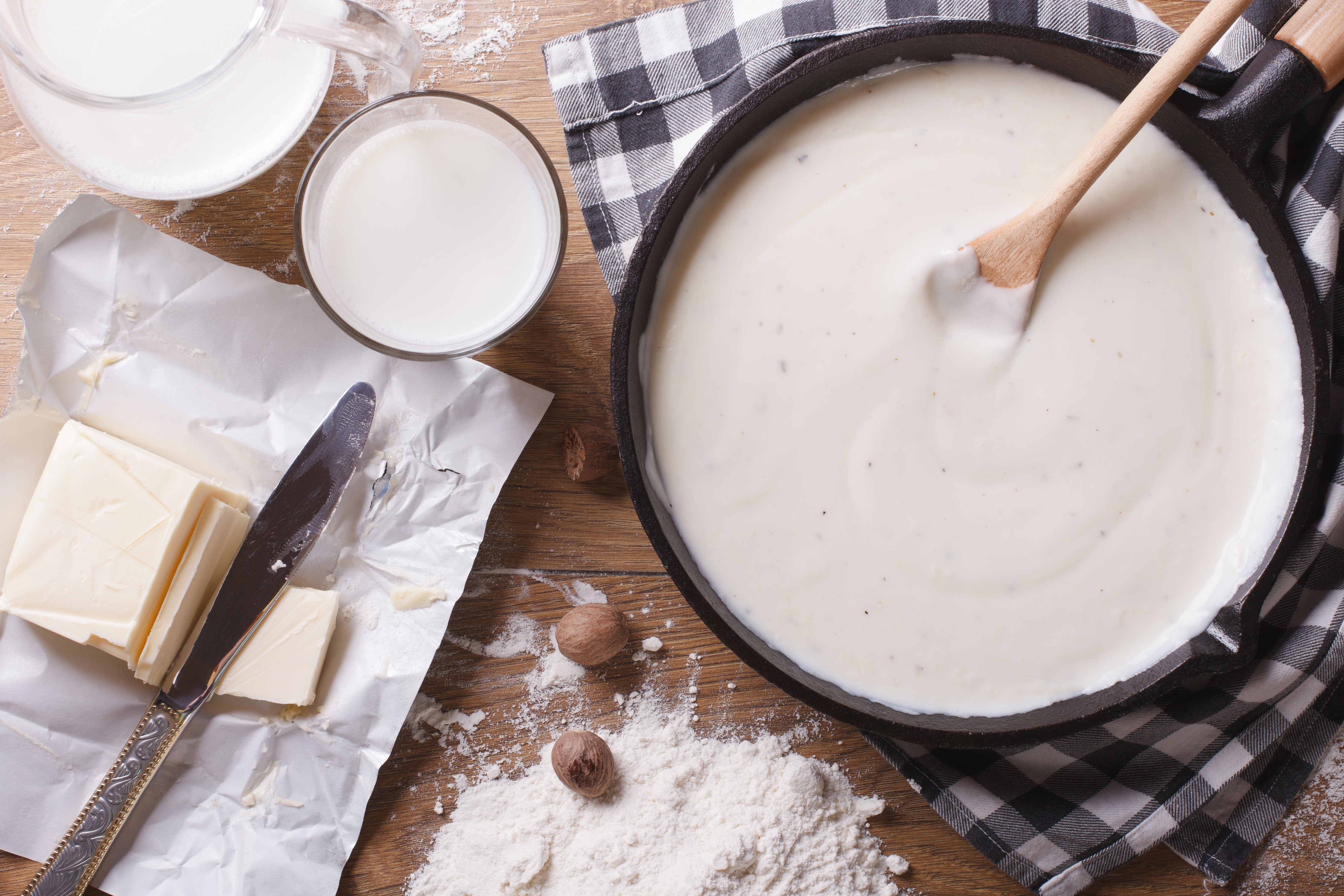 Preparation of bechamel sauce in a pan and ingredients on the table. horizontal top view close-up