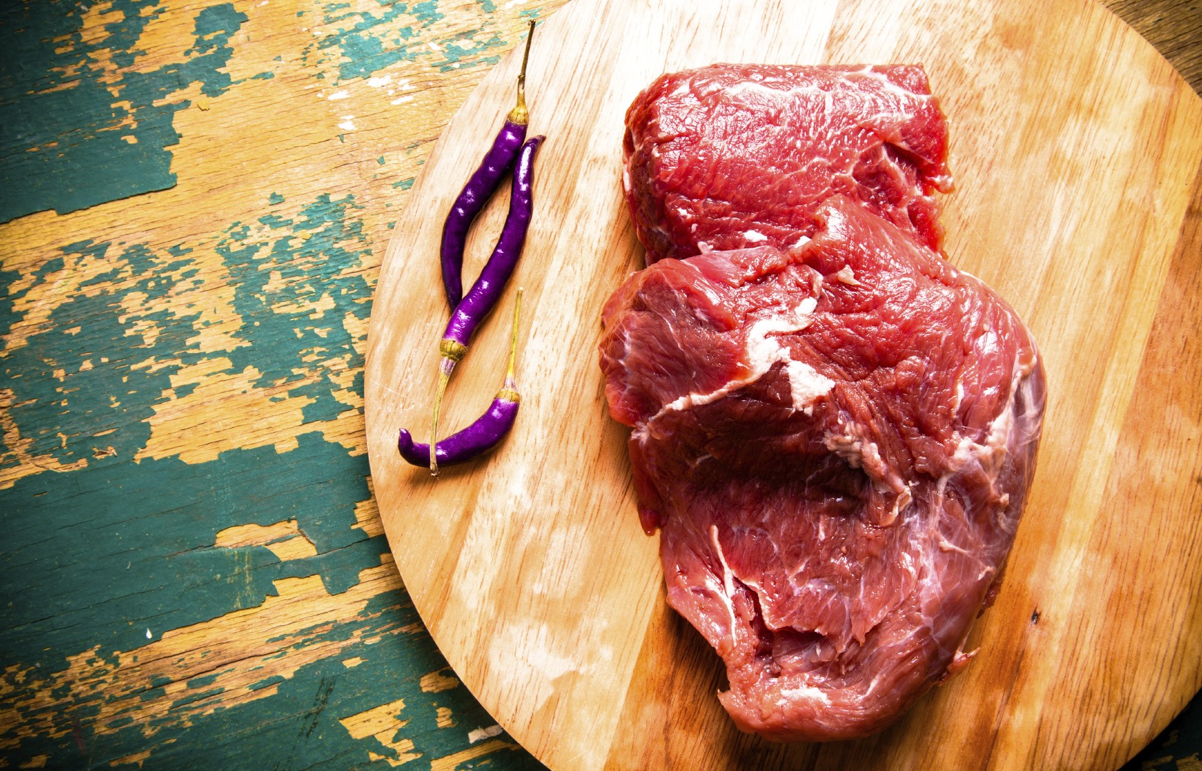 Fresh raw meat on light cutting board on an old wooden table. Ingredients for traditional turkish meal - Kuru fasulye. Toned.