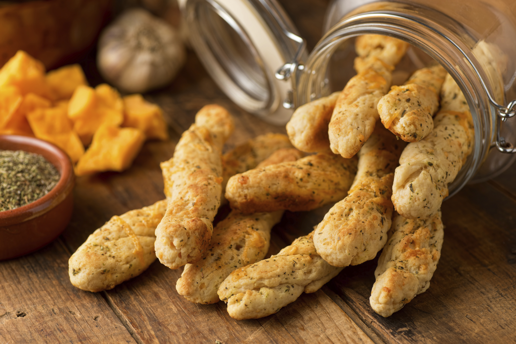 Freshly baked homemade garlic cheddar bread sticks on a rustic table top.