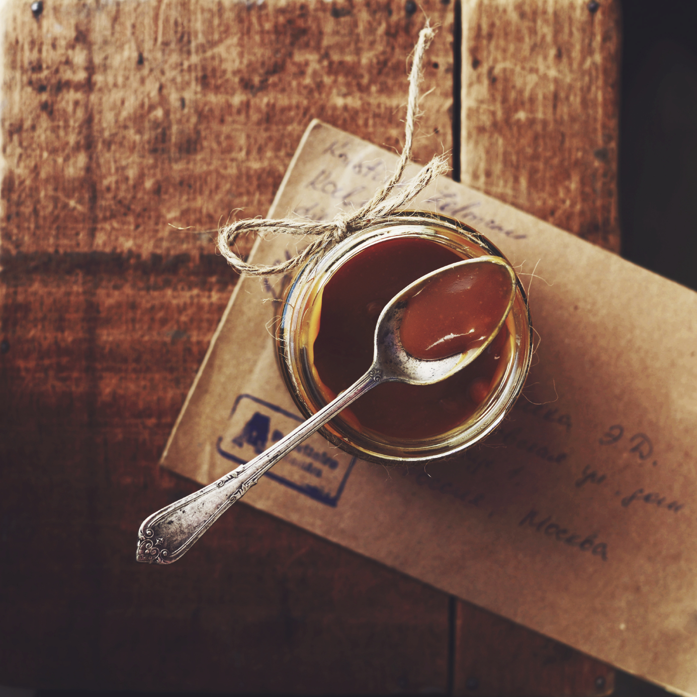 Homemade salted caramel sauce in glass jar on wooden background, table top
