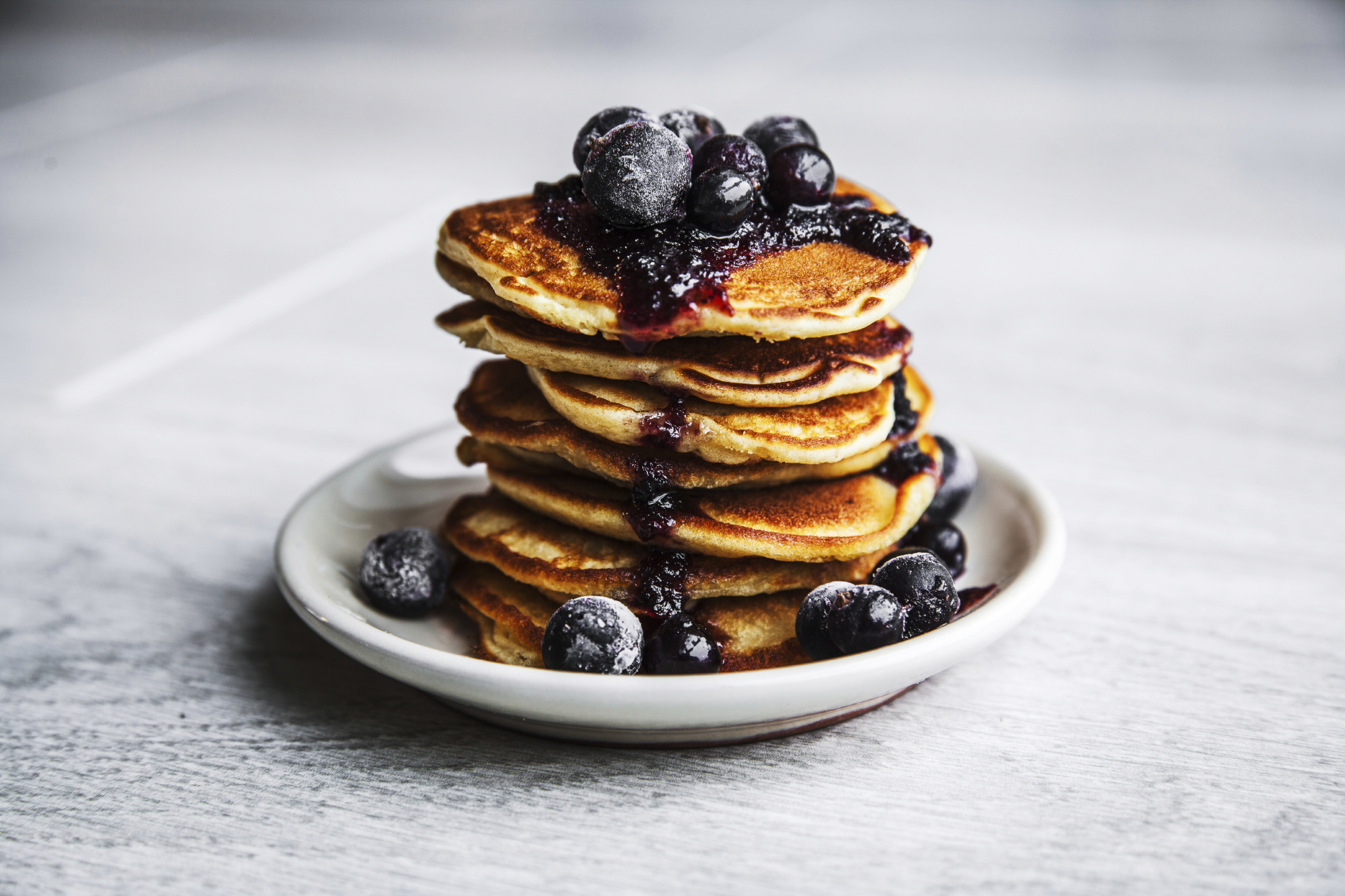 Picture of few pancakes with blackberries and sugar on wooden background
