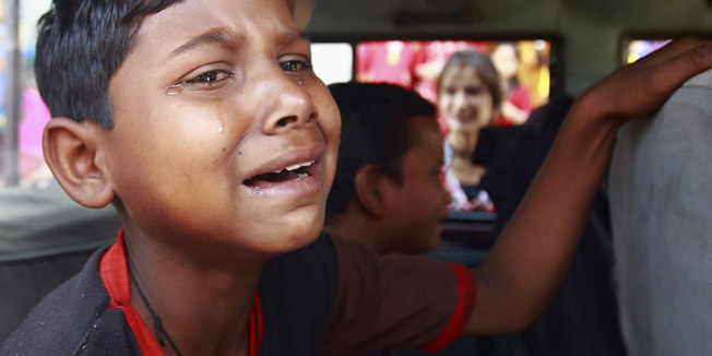 A boy cries as he sits inside a vehicle after being rescued from a sari embroidery factory in Kathmandu, a day after the World Day against Child Labour, June 13, 2013. A total of 39 children who were rescued from the factory were taken to a transit home by Central Child Welfare Board and will be handed over to their respective families. Over 80 embroidery factories are located in the Kathmandu Valley, where more than 500 children, mostly below 14 years of age, are employed, according to a researcher at Child Development Society (CDS).  REUTERS/Navesh Chitrakar (NEPAL - Tags: SOCIETY BUSINESS TEXTILE POLITICS EMPLOYMENT) - RTX10LXU