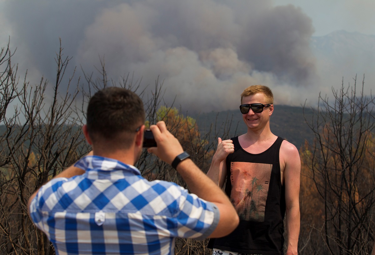 Turist se fotografira dok u pozadini gori šuma u Crnoj Gori koja se u ponedjeljak također muči s požarima.