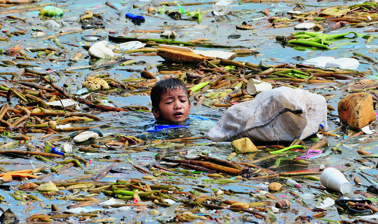 Dječak skuplja plastične boce duž obale Manilskog zaljeva