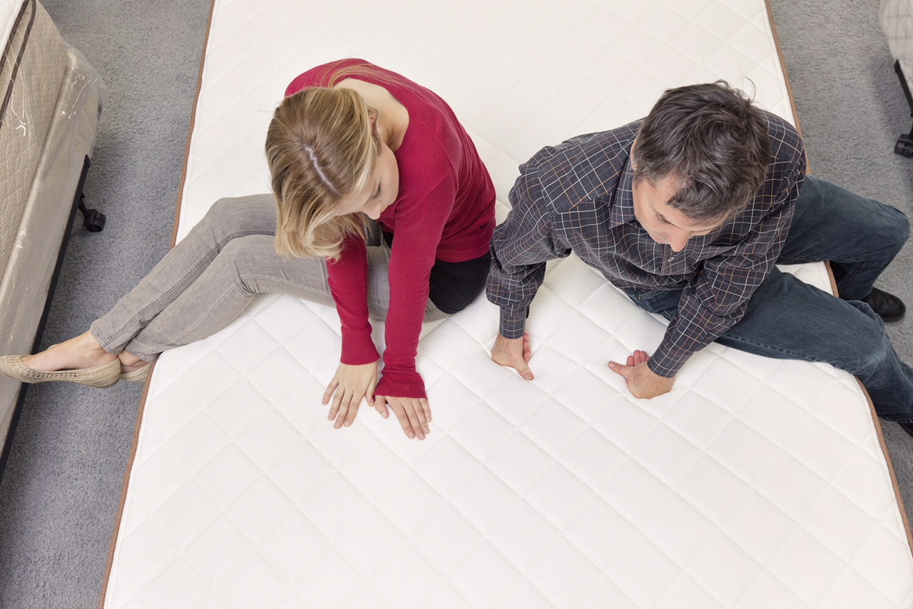 friends-sitting-on-mattress-in-furniture-store-29670417