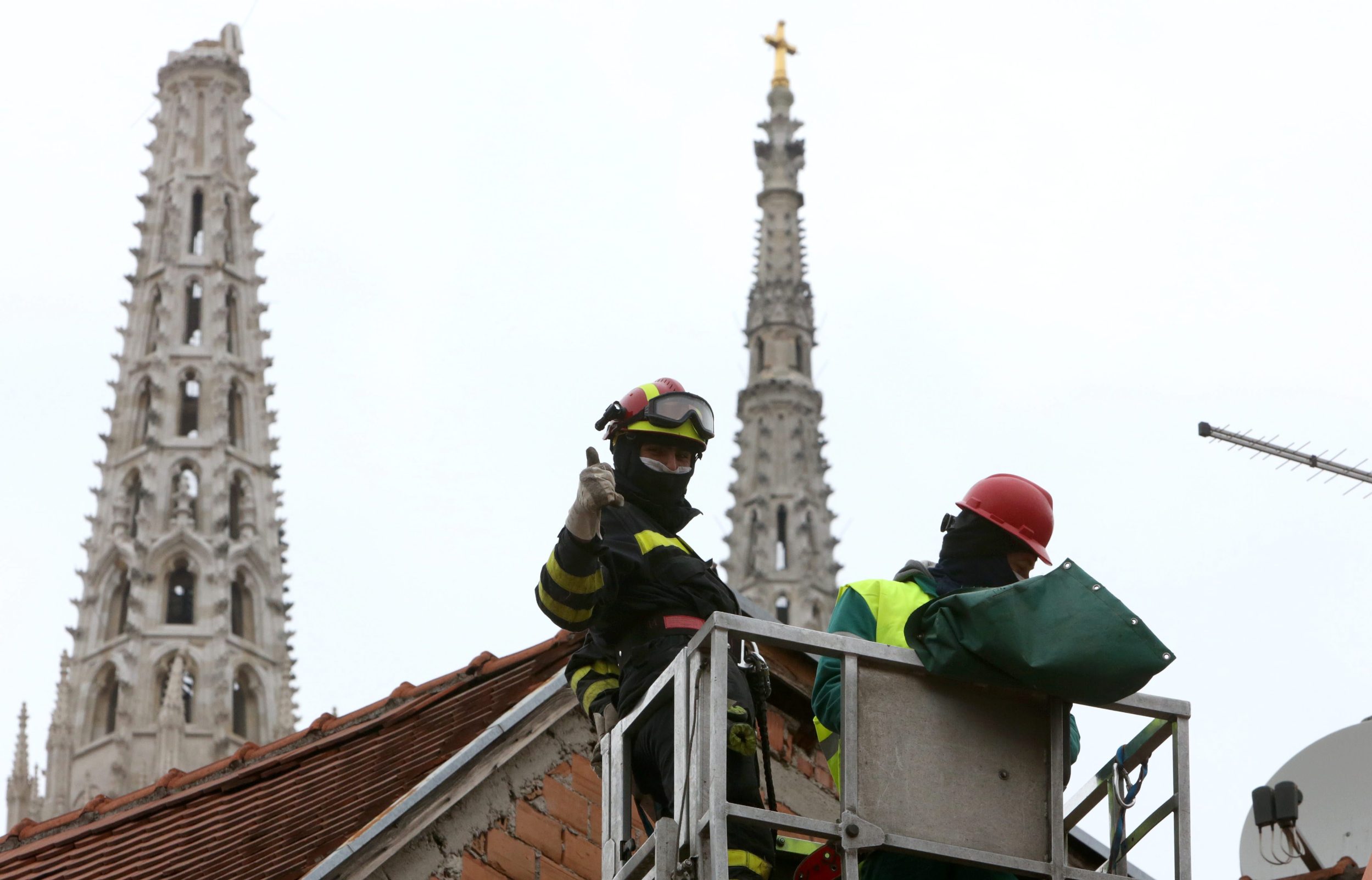Fireworkers are helping. Behind is cathedral without one of the crosses 