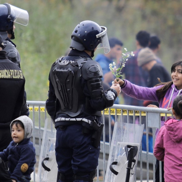 An Iranian migrant child Asal is seen across the iron barricade giving a flower to a Bosnian border police officer, on October 26, 2018 near Velika Kladusa town in Bosnia and Herzegovina. Hundreds of migrants including women and children continue their waiting around the border crossing between Bosnia and Croatia, to cross into neighboring Croatia, a member of the European Union.