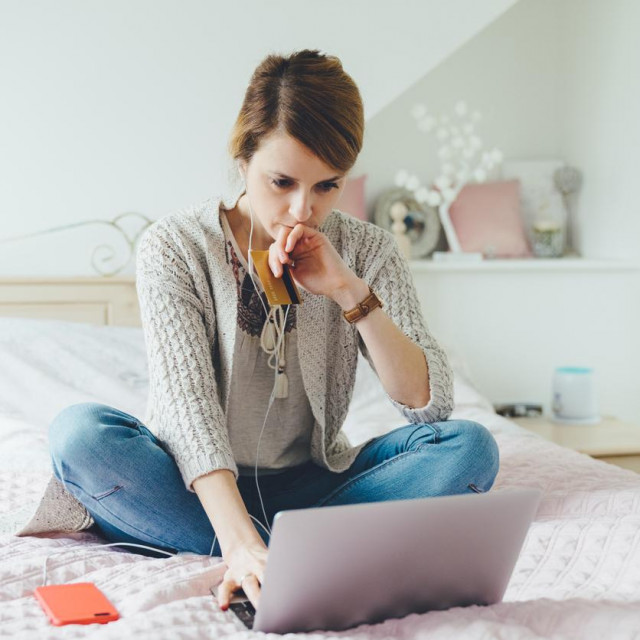 Young woman in the bedroom using laptop for planning the home finances