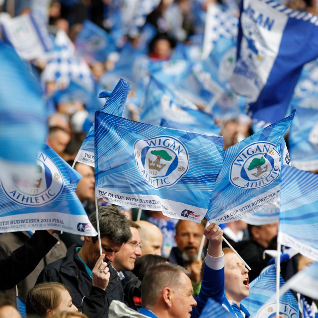 (FILES) In this file photo taken on May 11, 2013 Wigan Athletic fans wave flags before the start of the English FA Cup final football match between Manchester City and Wigan Athletic at Wembley Stadium in London. - Championship side Wigan will be handed a 12-point deduction after entering administration as the impact of the coronavirus pandemic starts to bite in English football. (Photo by IAN KINGTON/AFP)