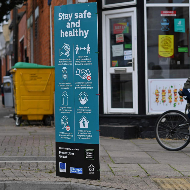 A youth cycles past a sign telling local residents to ”Social Distance” and advising on how to help ”Prevent the Spread” of coronavirus, in the North Evington district of Leicester, central England, on June 29, 2020. - The central English city of Leicester could be the country's first to face a local lockdown due to a rise in coronavirus cases, the UK's Home Secretary Priti Patel said on June 28. The Midlands city recorded 658 new cases in the two weeks up to June 16, many linked to fresh outbreaks at food production plants. (Photo by Ben STANSALL/AFP)