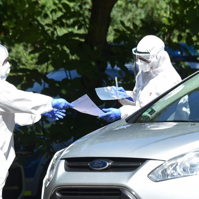 Zdravstveni radnici testiraju ljude iz automobila u Mammingu u južnoj Njemačkoj nakon izbijanja virusa na obližnjoj farmi 27.srpnja 2020.
 