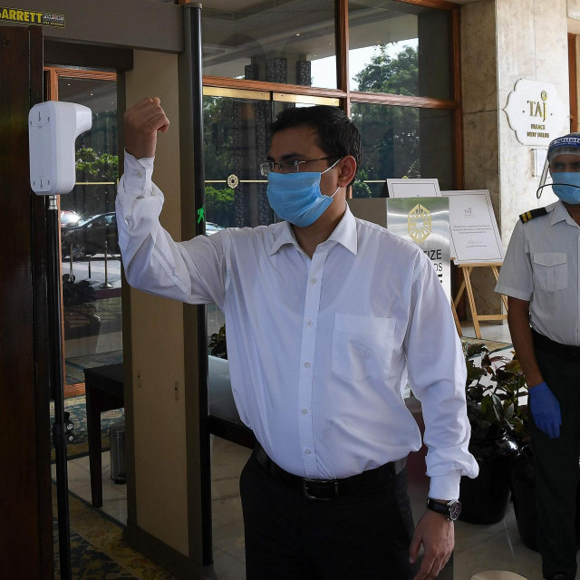 A guest checks his temperature at the entrance of the Taj Palace hotel in New Delhi on August 28, 2020. (Photo by Prakash SINGH/AFP)