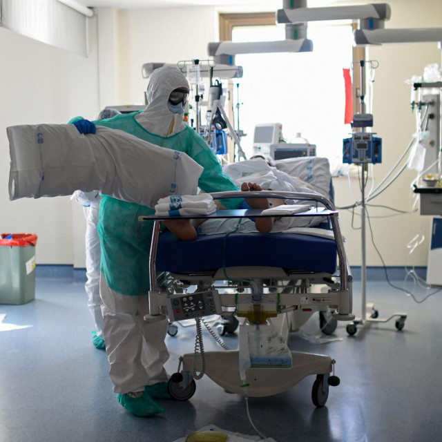 A healthcare worker in protective suit attends a COVID-19 patient at the Intensive Care Unit (ICU) of the Ramon y Cajal Hospital in Madrid on October 15, 2020. (Photo by OSCAR DEL POZO/AFP)