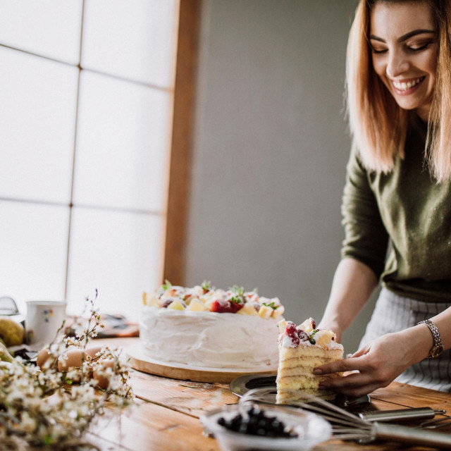 Woman cut a piece of cake for the birthday celebrant