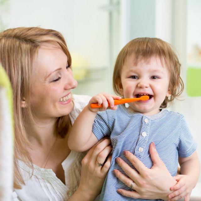 mother teaching son child teeth brushing in bathroom
