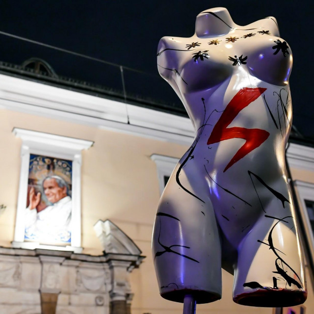 Crvena munja simbol je prosvjeda protiv zakona; u pozadini fotografija nadbiskupa Mareka Jedraszewska