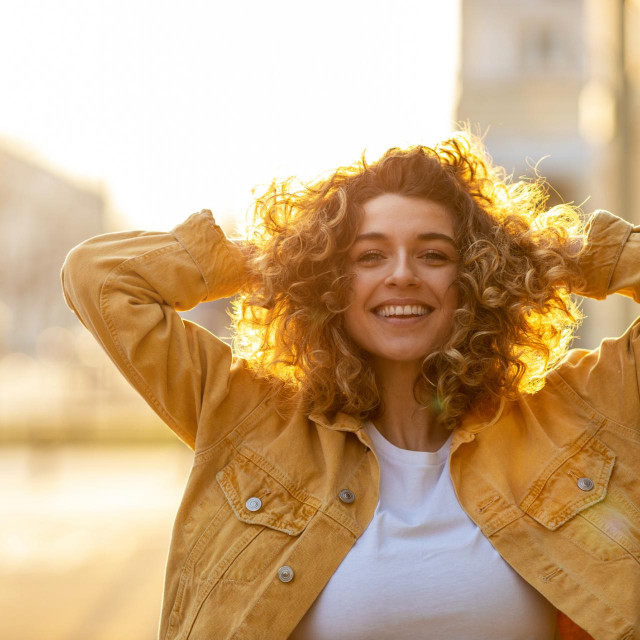 Portrait of young woman with curly hair in the city