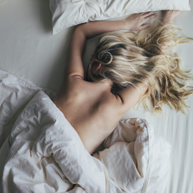Top view of a young blonde woman sleeping on her bed in the morning.