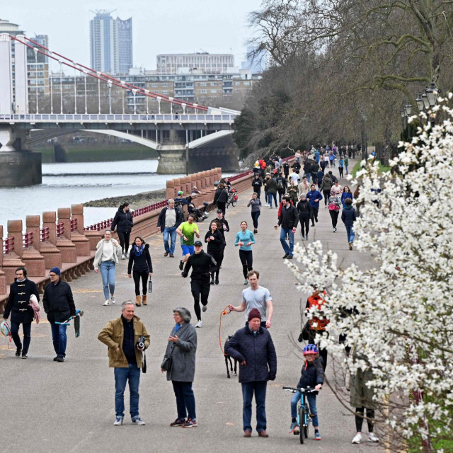 People take their daily exercise beside the River Thames in Battersea Park in London on March 28, 2021. - From Monday, England's stay-at-home order to combat the spread of the coronavirus will be relaxed to enable groups of up to six people to meet outside. The government plans to allow outdoors drinking in pub gardens, and non-essential retail such as hairdressers, from April 12. (Photo by Justin TALLIS/AFP)