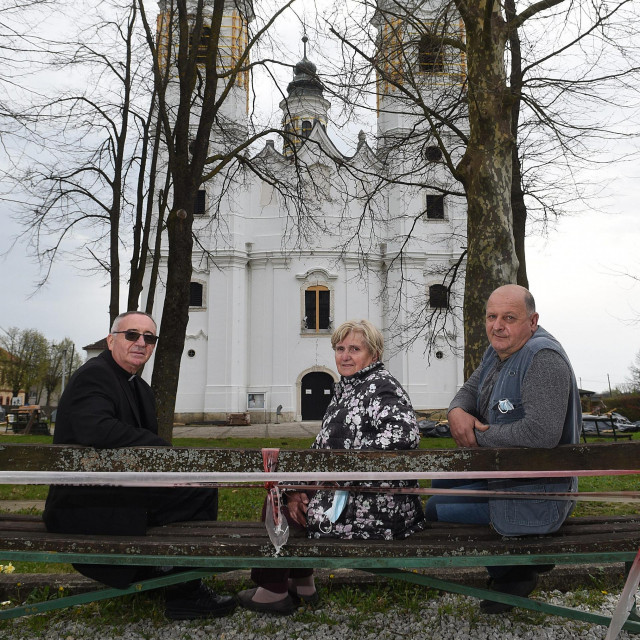 Župnik Dragutin Papić, župljanka Ivanka Barić i crkveni sakristan Franjo Palaić na klupi ispred oštećene seoske crkve
 