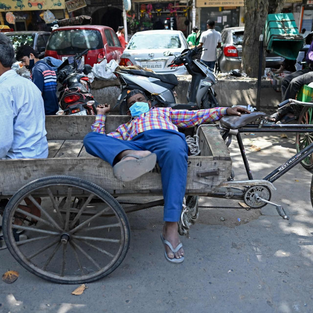 Rickshaw drivers rest along a street in the old quarters of New Delhi on April 19, 2021, as India's capital will impose a week-long lockdown from tonight, officials said, while the megacity struggles to contain a huge surge in Covid-19 cases with hospitals running out of beds and oxygen supplies low. (Photo by Sajjad HUSSAIN/AFP)