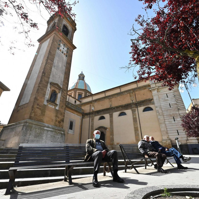 People sit near the Basilica Cathedral of San Giuliano at Piazza Umberto I in Caltagirone, Sicily, on April 27, 2021. - Italy has long suffered one of the lowest birth rates in Europe, but the situation has been exacerbated by the coronavirus pandemic -- saddling the country with problems that go well beyond empty cribs. (Photo by Andreas SOLARO/AFP)