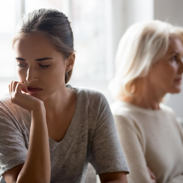 Angry offended senior Caucasian mother and adult grownup daughter sit separate at home ignore talking after family fight. Unhappy mature mom and child avoid speaking. Generation gap concept.